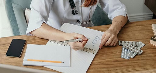 Médica escrevendo em seu caderno