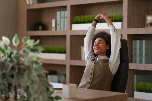Uma mulher está esticando os braços em frente a uma estante de livros.