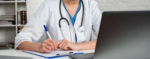 Uma mulher de jaleco branco está escrevendo em um bloco de notas.