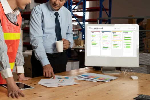 Duas pessoas em um armazém olhando para uma tela de computador.