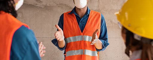 Três pessoas usando equipamentos de segurança e conversando.