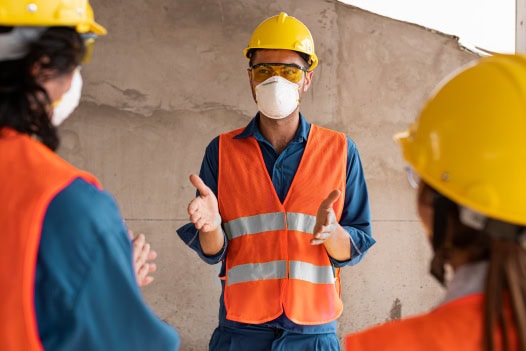 Três pessoas usando equipamentos de segurança e conversando.